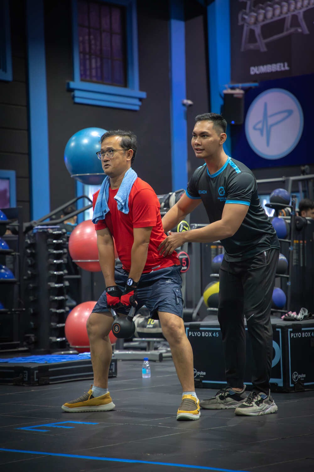 Trainer helping man with squat