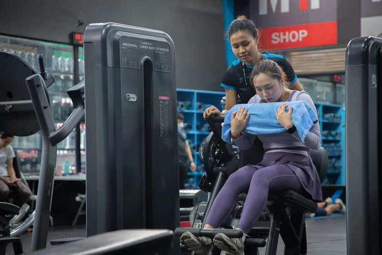 Trainer assisting woman with leg press